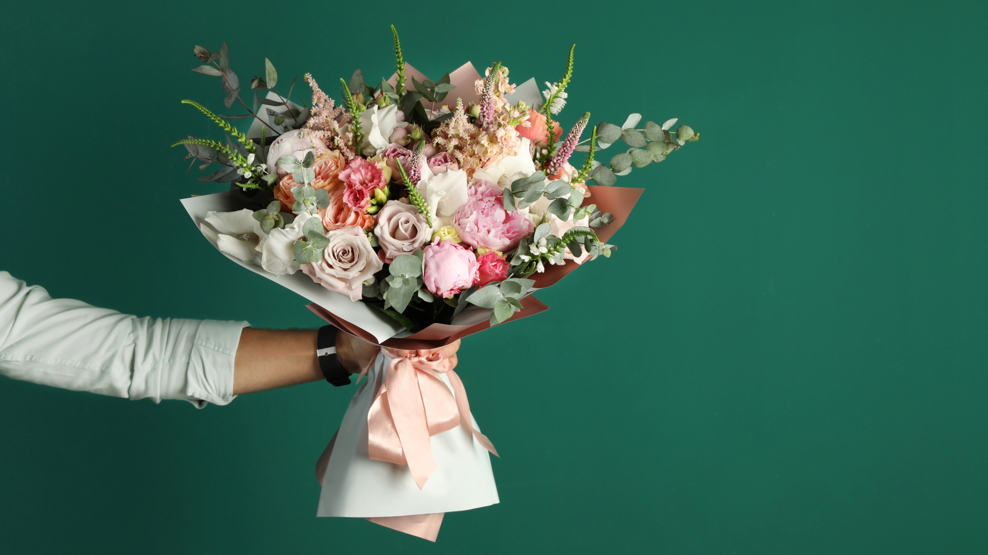 Bouquet of flowers held by a person against a green background