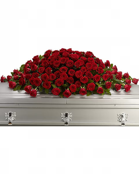 Silver casket with a large arrangement of red roses on a white background