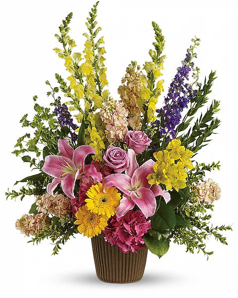 Brown basket holding pink lilies, yellow daisies, and greenery floral bouquet on white backdrop